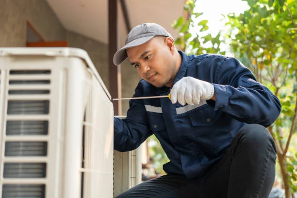 Technician checking connections on an outdoor heat pump unit