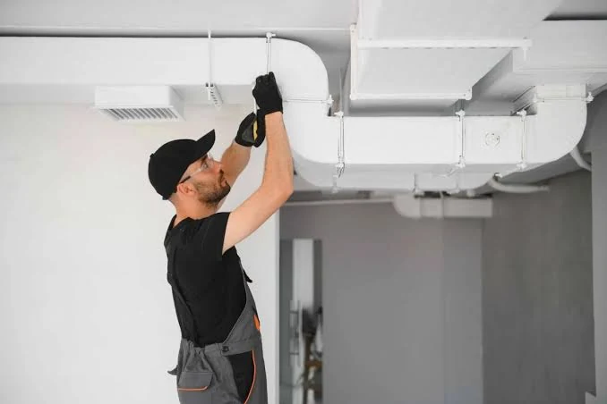 Technician inspecting overhead ductwork and ventilation
