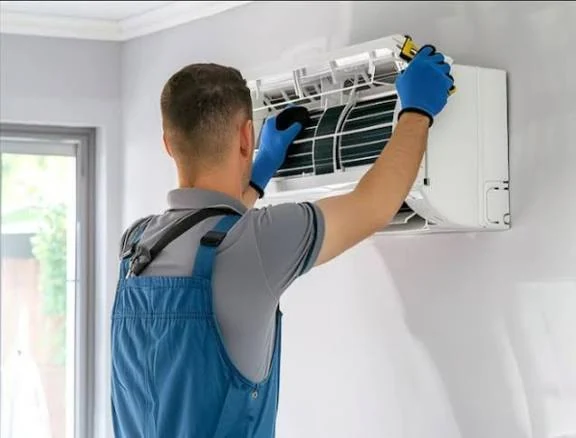 Technician removing a filter from a wall-mounted indoor unit