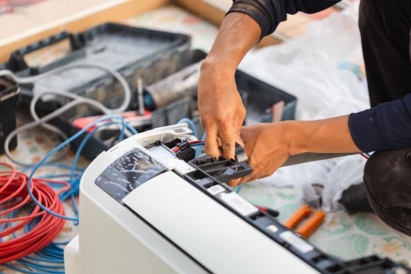 Hands checking internal components of an indoor air conditioning unit