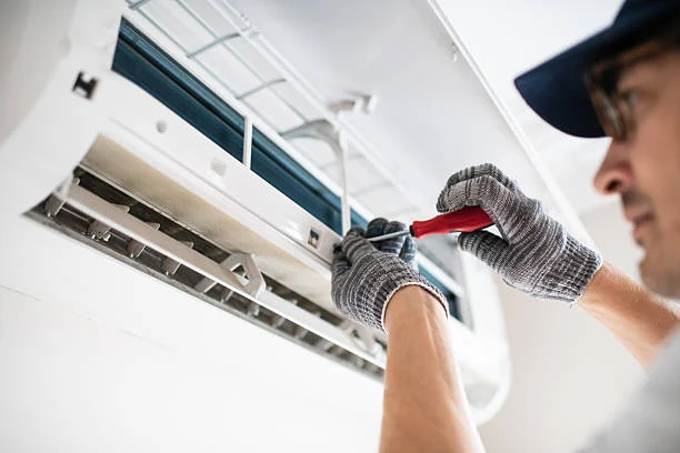 Technician adjusting components inside a wall-mounted air conditioner